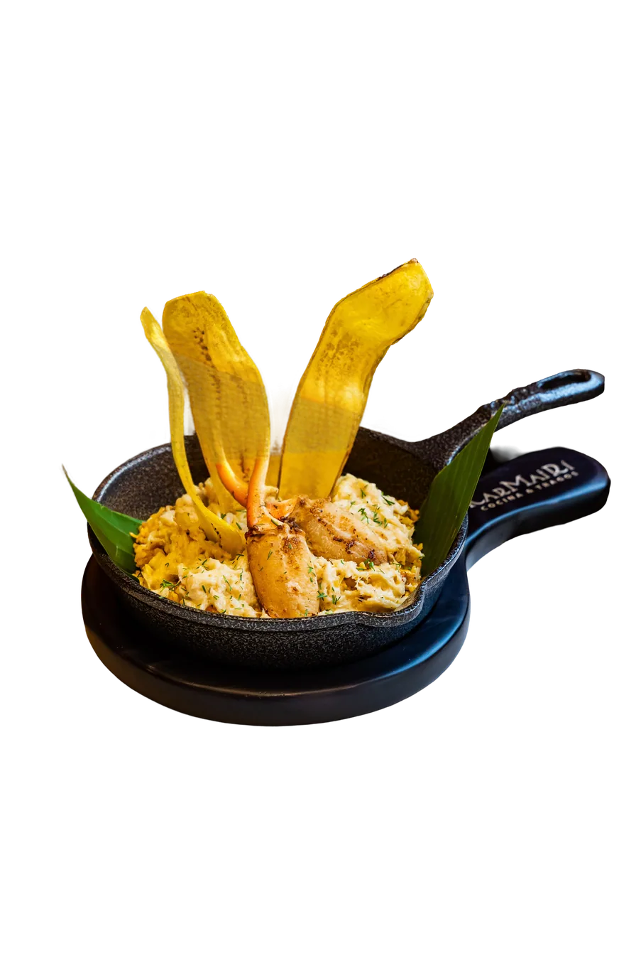 Arroz cremoso con cangrejo y chips de plátano en sartén de hierro