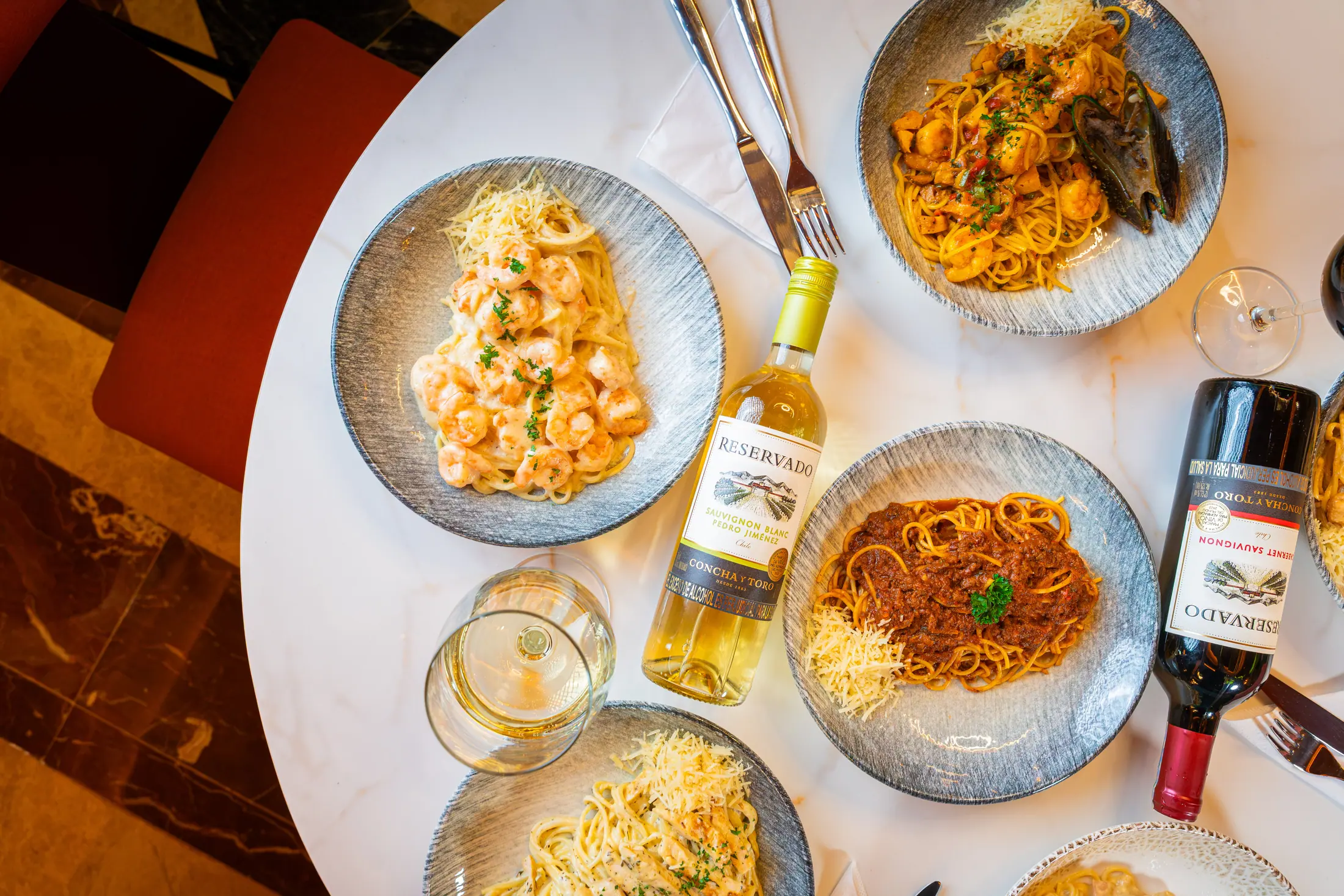 Mesa servida con pastas de mariscos y vinos